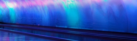 Blue, purple and pink lights illuminate a metal tunnel with a flat escalator in Detroit